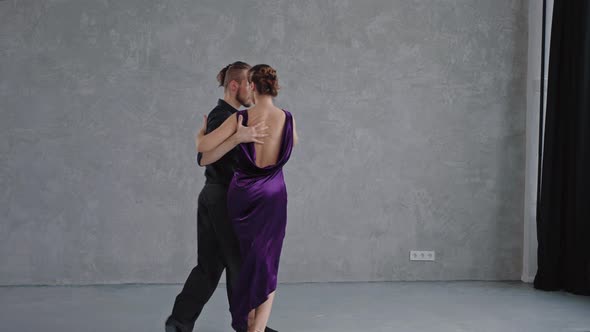 Camera Slowly Moving to a Pair Sensually Dancing a Tango in a Grey Studio