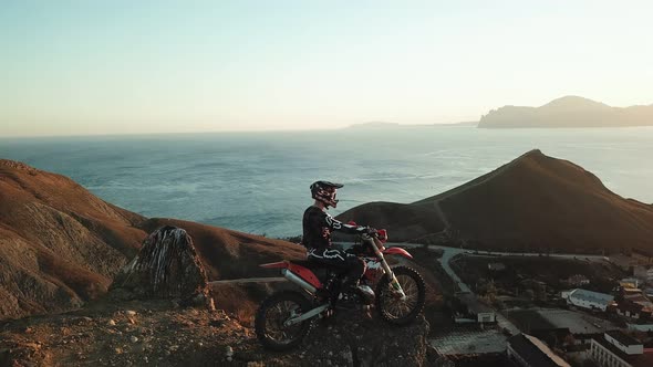 Drone View of Man on Motorbike Extremely Rides Across the Hills with Black Sea on Background in