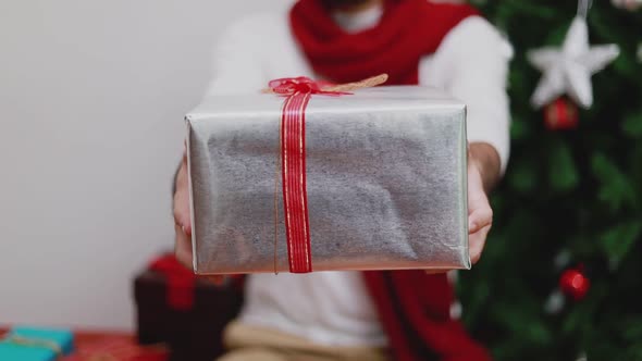 Asian man presents a gift box in front of the camera.