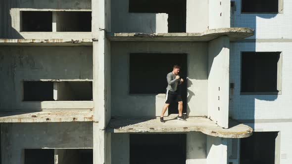 Sportsman Shadow Boxing on Balcony of Unfinished Building