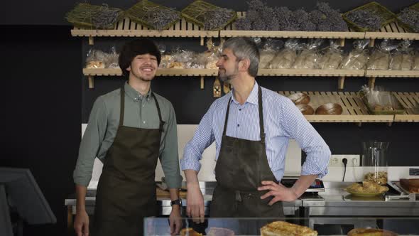 Close Up Portrait of Happy Father and Son Family Business Owners High Five in Their Bakery Store alt