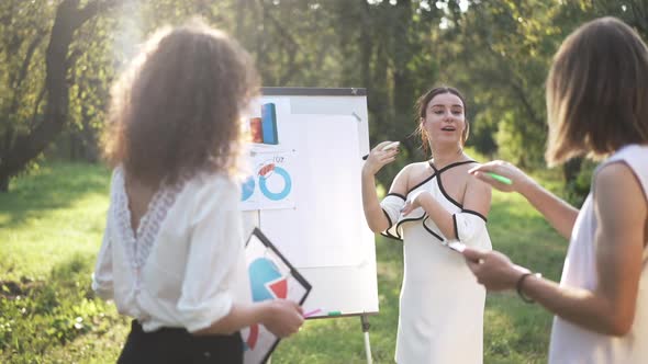 Young Beautiful Woman Explaining Business Strategy in Spring Park Talking to Colleagues in Slow alt
