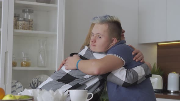Mother Comforting Her Teenager Son with Down Syndrome at Home