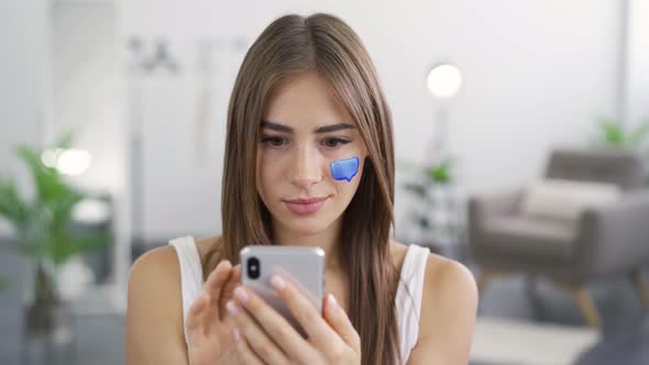 Close-up Portrait of Young Pleasant Woman Using Her Mobile Phone Sitting at Home alt