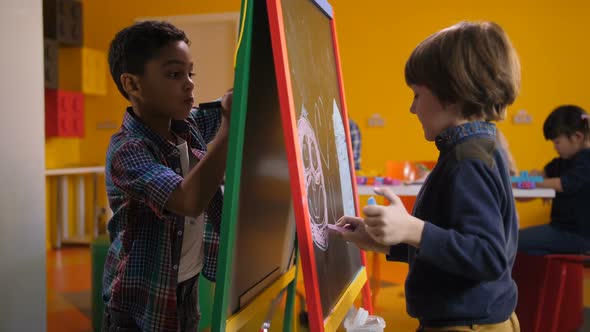 Boys Drawing with Colorful Chalks on Easel Board