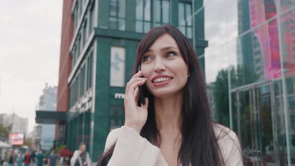 Attractive Young Business Woman Talking Using Mobile Phone Against the Background of Urban City