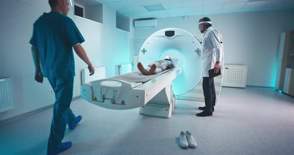 Medical Practitioners Finishing CT Scan of Black Man alt