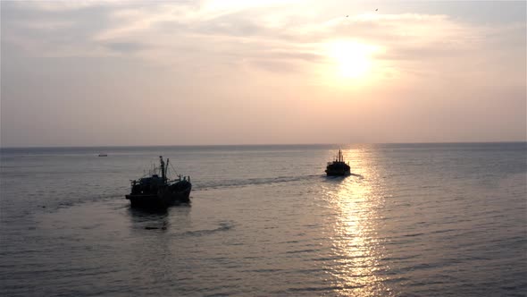 Two Fishing Boats Are Sailing to The Sunset