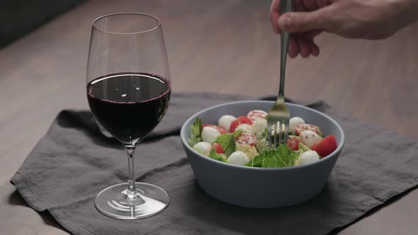 Slow Motion Man Eat Salad with Tomatoes and Mozzarella with Glass of Red Wine