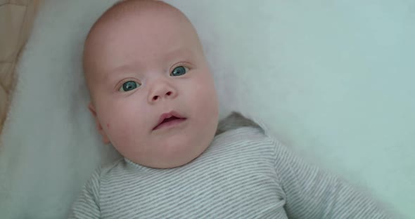 Perplexed Newborn Baby Lying in Bed and Looking at Camera alt