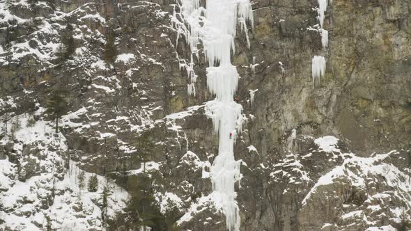 Extreme wide aerial showing climber scaling ice cascade Maineline, Mount Kineo alt