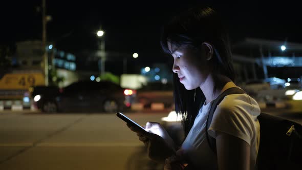 Asian woman smile and using a smartphone on a street in Downtown at night.