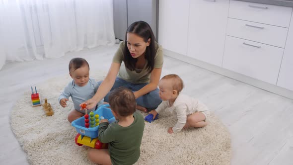 Asian Mom and Toddler Triplets Sitting and Playing with Toys alt