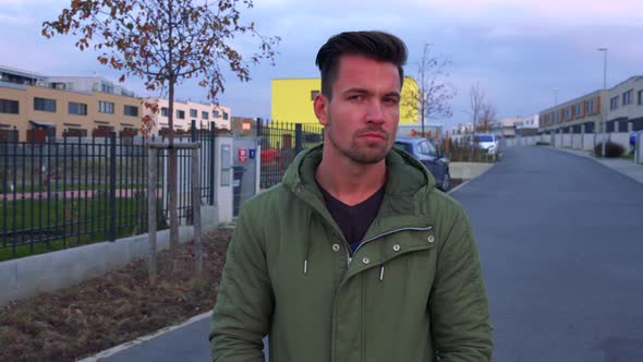 A Young, Handsome Man Shuffles Back and Forth on a Road in a Neighborhood and Looks Around alt