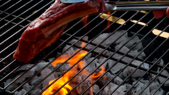 Chef Puts Steak Using Tongs on the Grill Grate alt