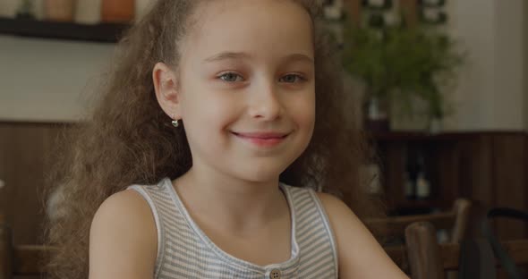 Portrait of Funny Little Girl Smiling Child Looking at Camera Sitting at the Table at Home Cute Kid alt