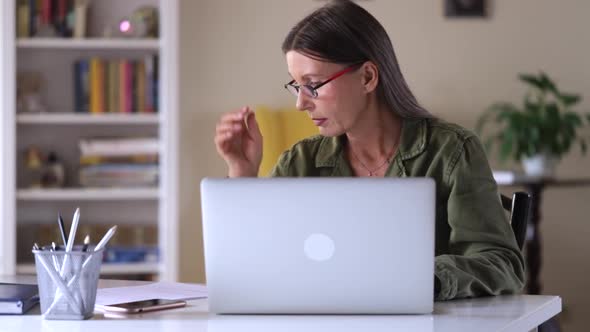 Beautiful Elderly Woman is Working with Laptop at Table in House During Selfisolation Spbi alt