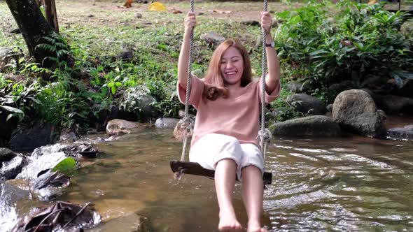 Slow motion of a woman playing swing in waterfall stream