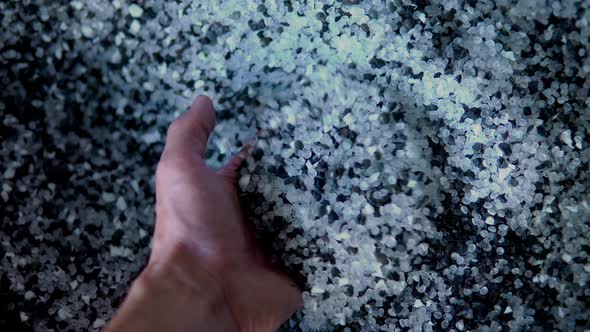 Plastic Black and White Granules are Poured From the Hand