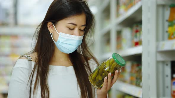 Asian Woman Reading Label on Pickles at Store alt
