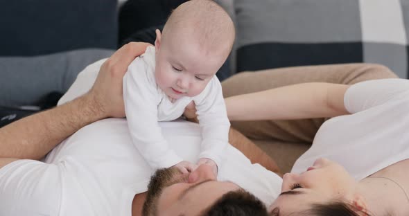 Baby girl lay on father and mother in bed