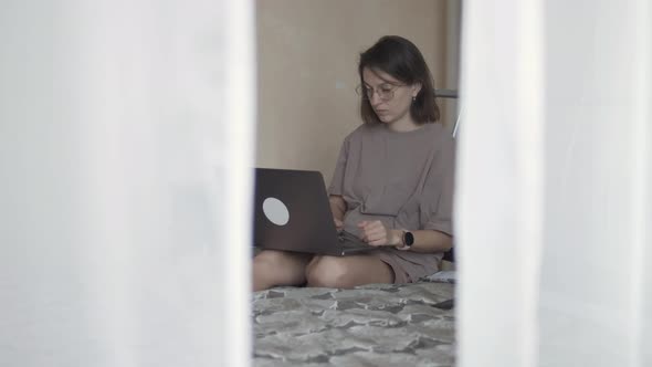 Woman Sitting on Bed and Working Remotely