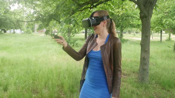 Sexy Girl In A Virtual Reality Helmet Uses A Virtual App In The Park