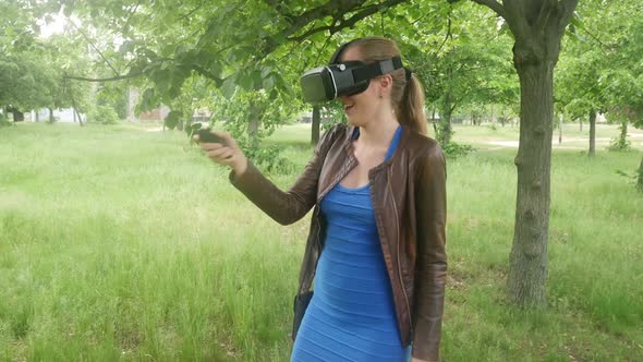 Sexy Girl In A Virtual Reality Helmet Uses A Virtual App In The Park alt