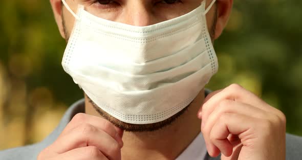 Portrait of young man putting medical mask on face.