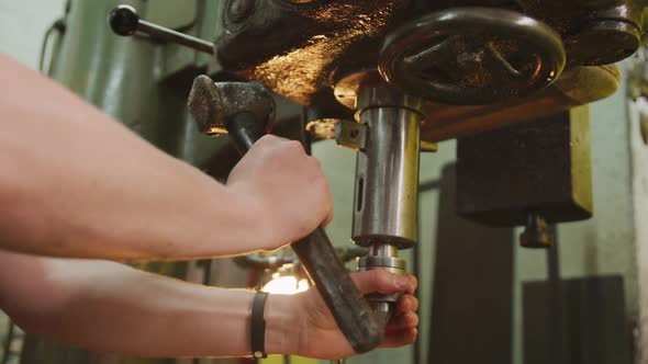 Caucasian male hands factory worker at a factory standing at a workbench and operating machinery alt