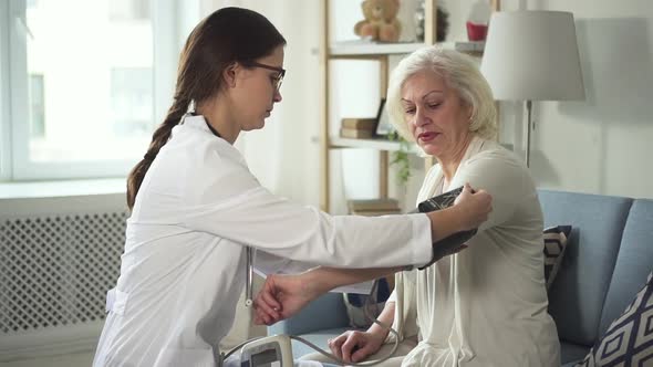 Assistant of Doctor Puts Pressure Gauge on Hand Senior Woman alt
