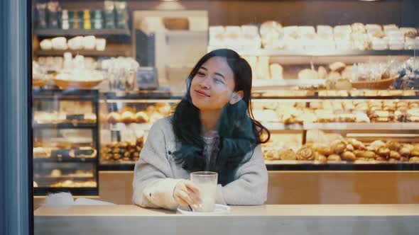 Woman is Looking at the Street While Drinking Coffee Alone in Cafe