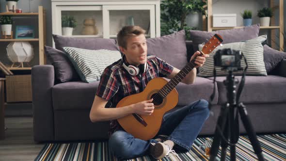 Handsome Guy Vlogger Is Recording Video for Subscribers Teaching To Play the Guitar Holding Musical alt