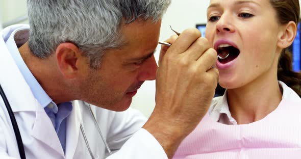 Dentist examining a female patient with tools alt