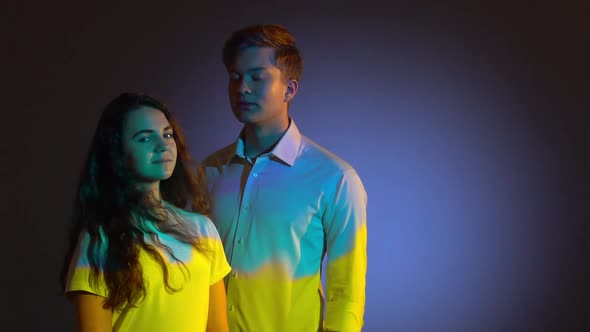 Two Teenagers Posing in Studio with Projector Reflection of Blue and Yellow Ukrainian Flag