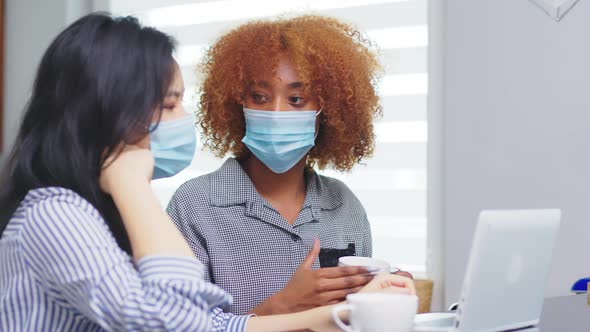 New Normal. Women Collegues with Medical Mask Working on the Project with Protective Measures alt
