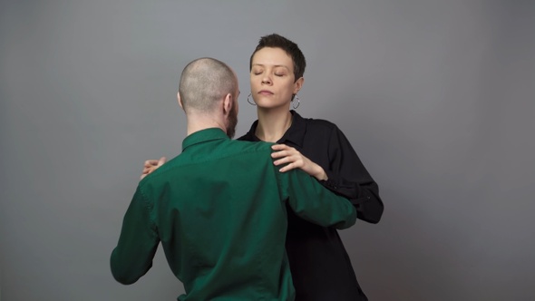 Romantic couple dancing on gray background. Slow blues dance.