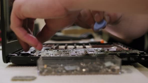 Closeup of a Male Engineer Repairing a Laptop in the Workshop alt