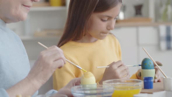 Grandma and Granddaughter Having Fun while Painting Easter Eggs alt