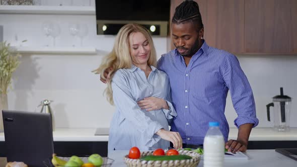 Pregnant Caucasian Woman Tasting Organic Ingredients for Healthful Salad As African American Man alt