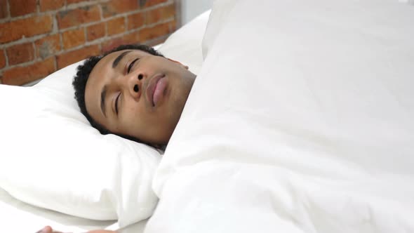 Uncomfortable African Man Sleeping in Bed at Night, Restlessness alt