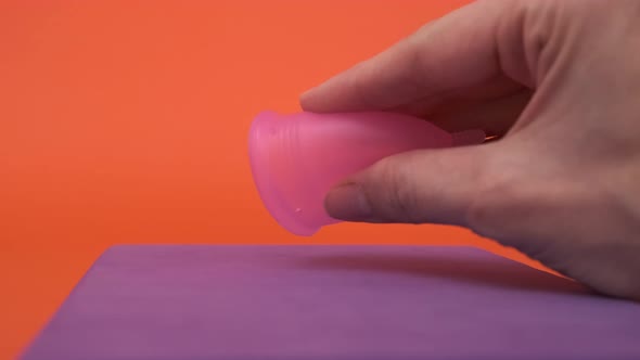 Pink Menstrual Cup Closeup on Orange Background