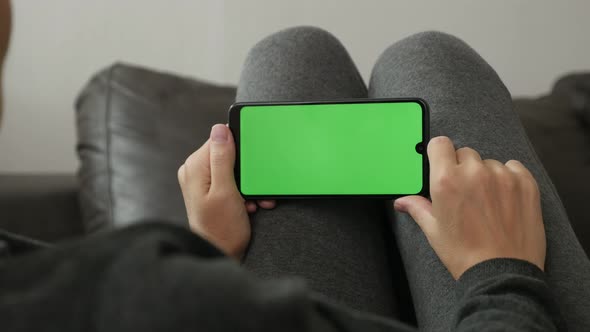 Woman at home holds mobile phone with green screen display 4K footage