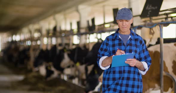 Farmer Gesturing While Writing on Clipboard Against Barn alt