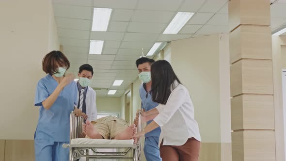 Group of doctor, nurse and surgeon move seriously injured patient lying on a stretcher in hospital. alt