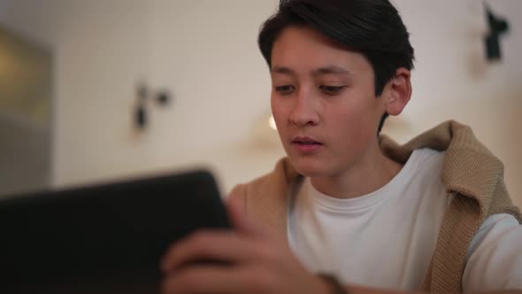 Handsome Asian man looking at tablet and drinking juice alt