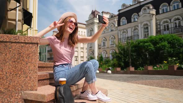 Beautiful Young Woman Tourist with Takeout Coffee Sitting on Stairs Using Smartphone alt