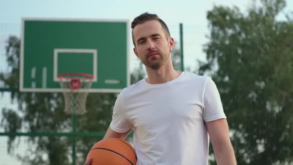 Guy Holding a Ball While Posing at Basketball Court alt