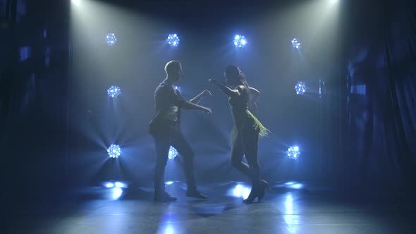 Young Couple Dancing Latin Music. Bachata, Merengue, Salsa. Shot in a Dark Studio with Neon Lights alt