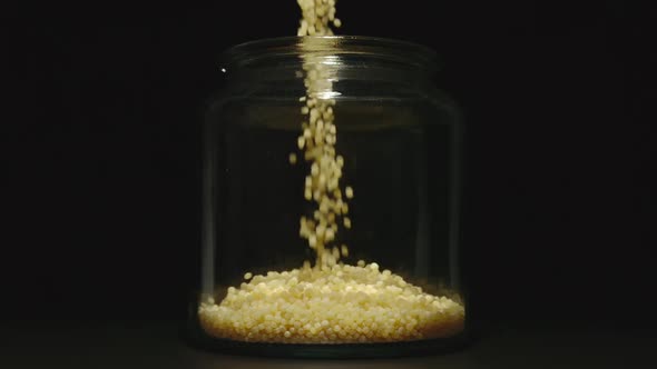 SLOW MOTION: Couscous Grains Pouring Into A Glass Jar alt